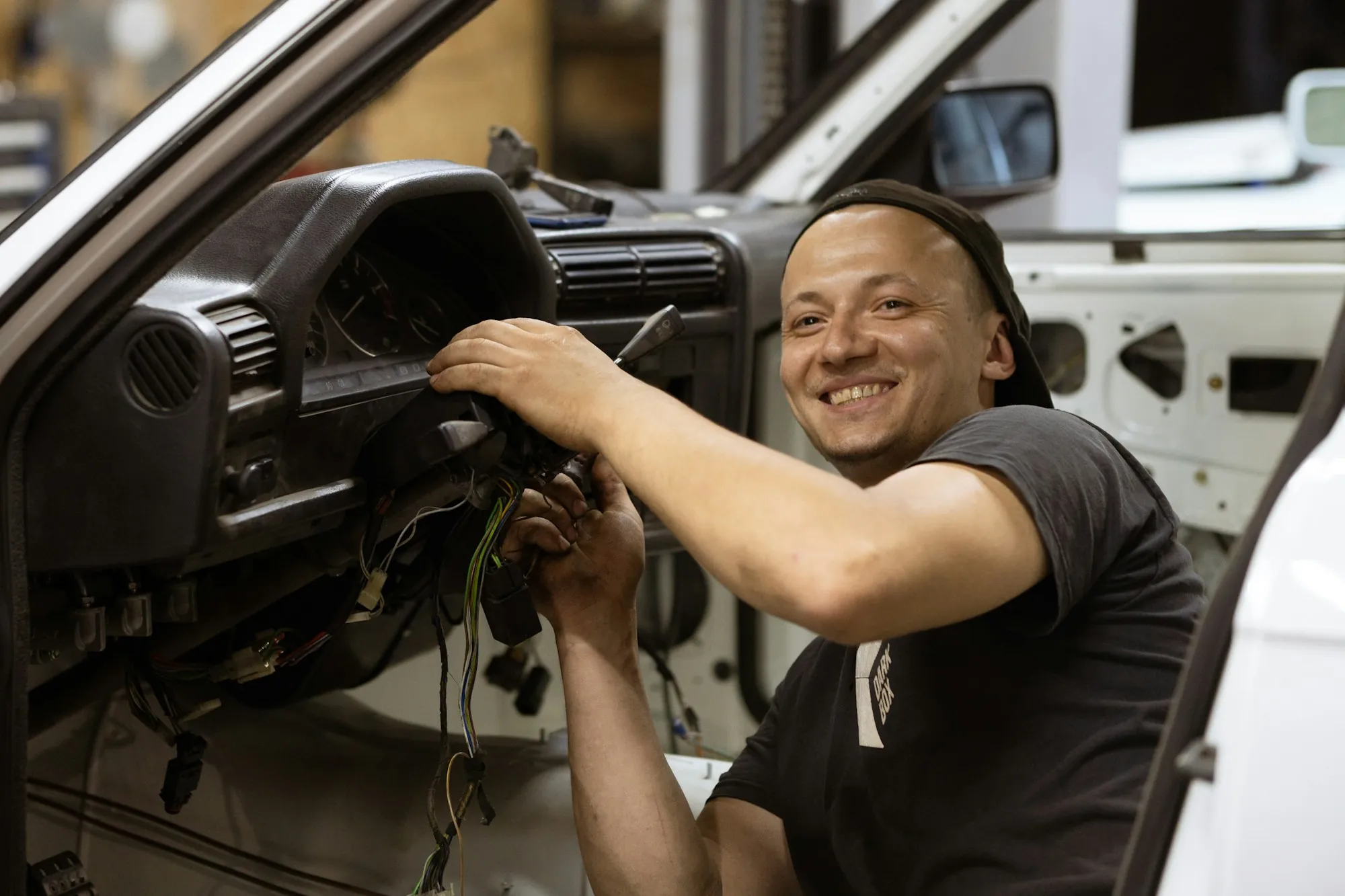 Technician working inside a car's dashboard with a smile