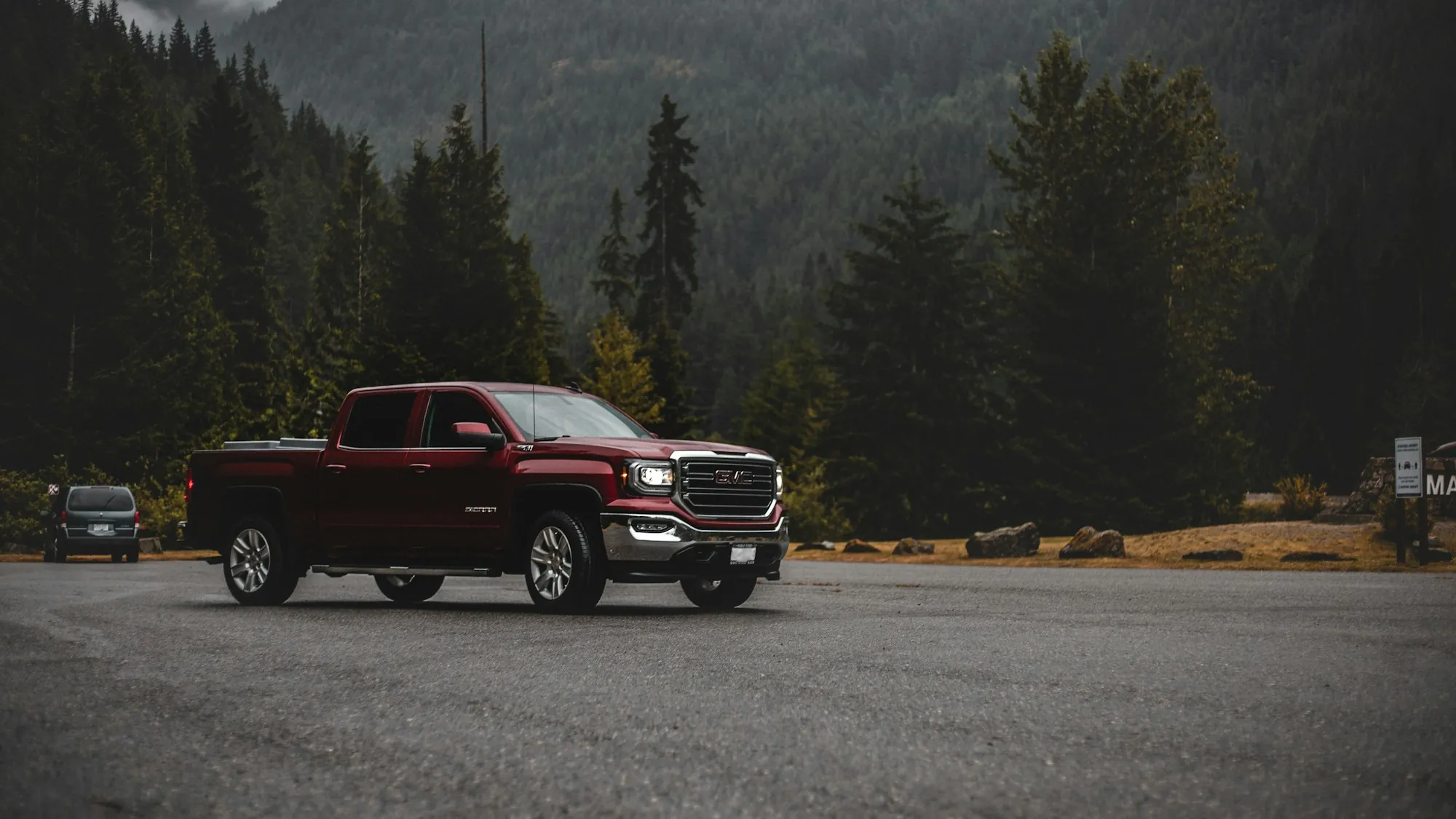 Red pickup in a forest clearing on a cloudy day