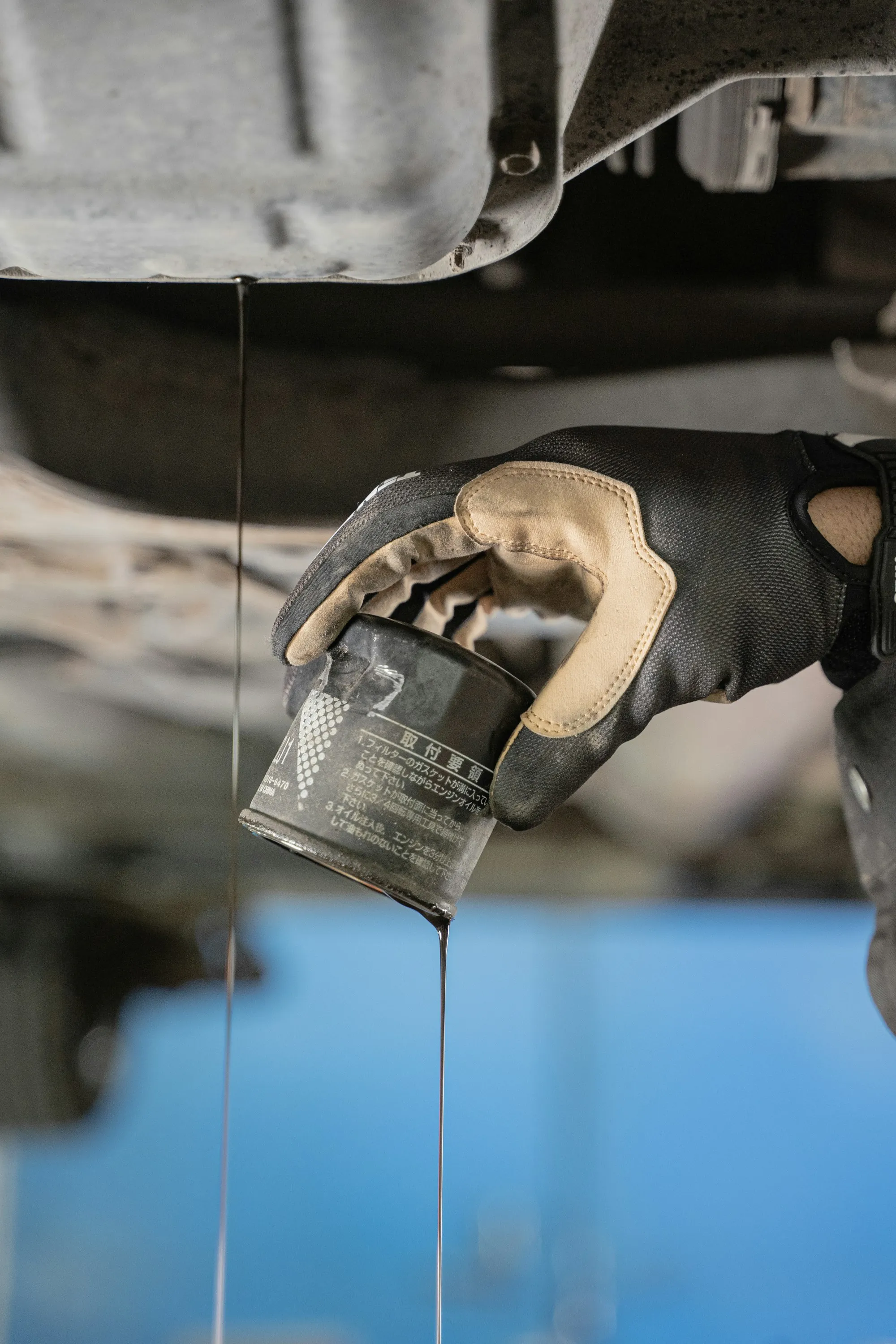 Oil filter being unscrewed beneath a vehicle