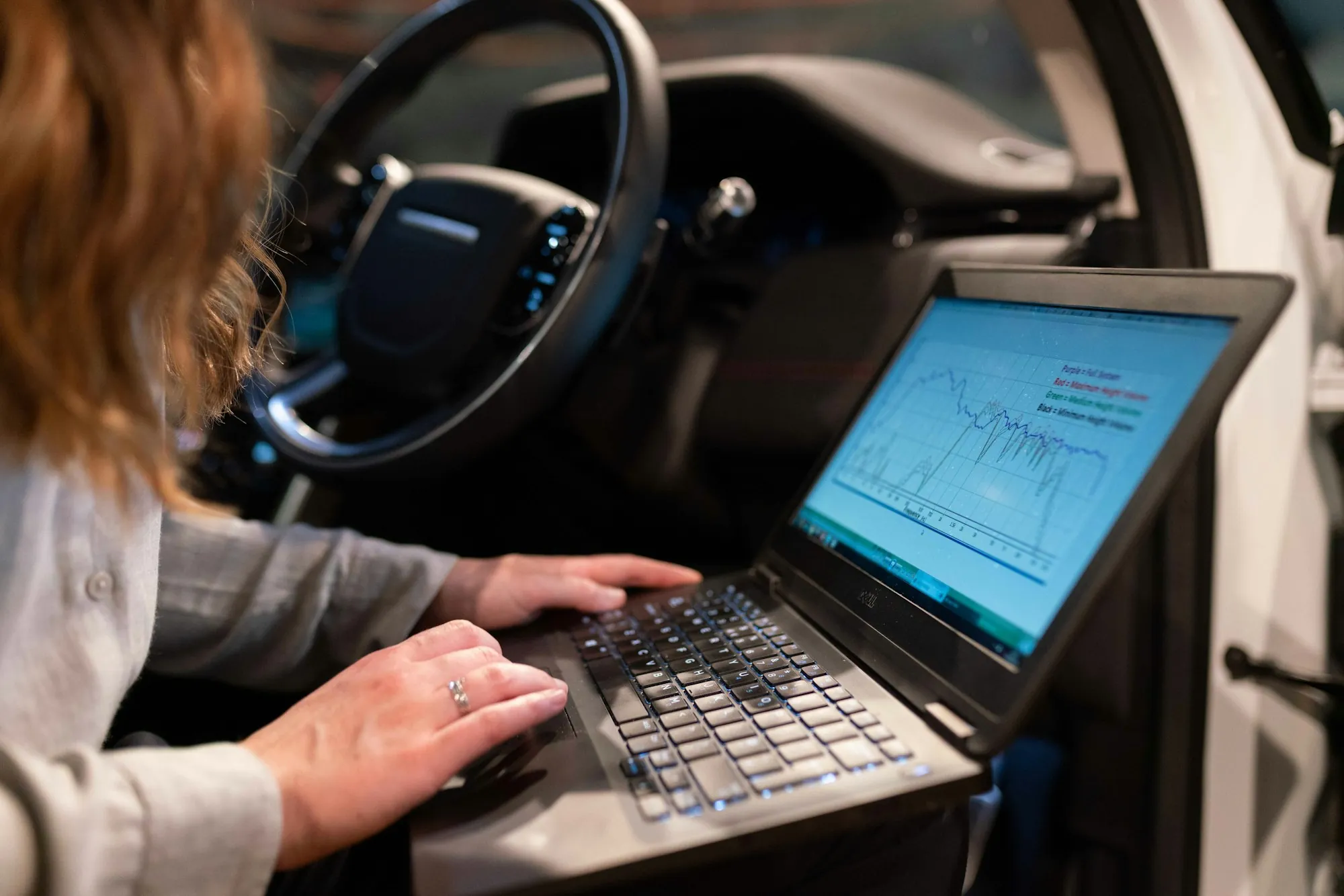 Mechanic using a diagnostic laptop beside the driver's seat