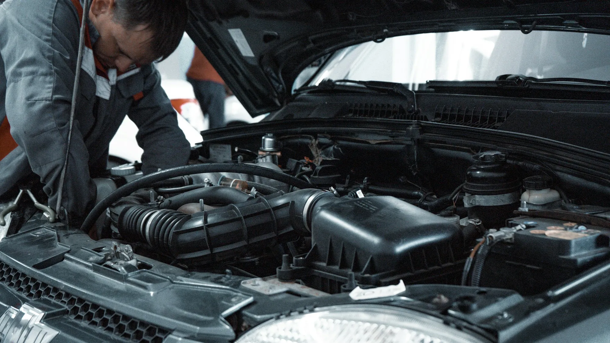 Two mechanics working under the open hood of a car