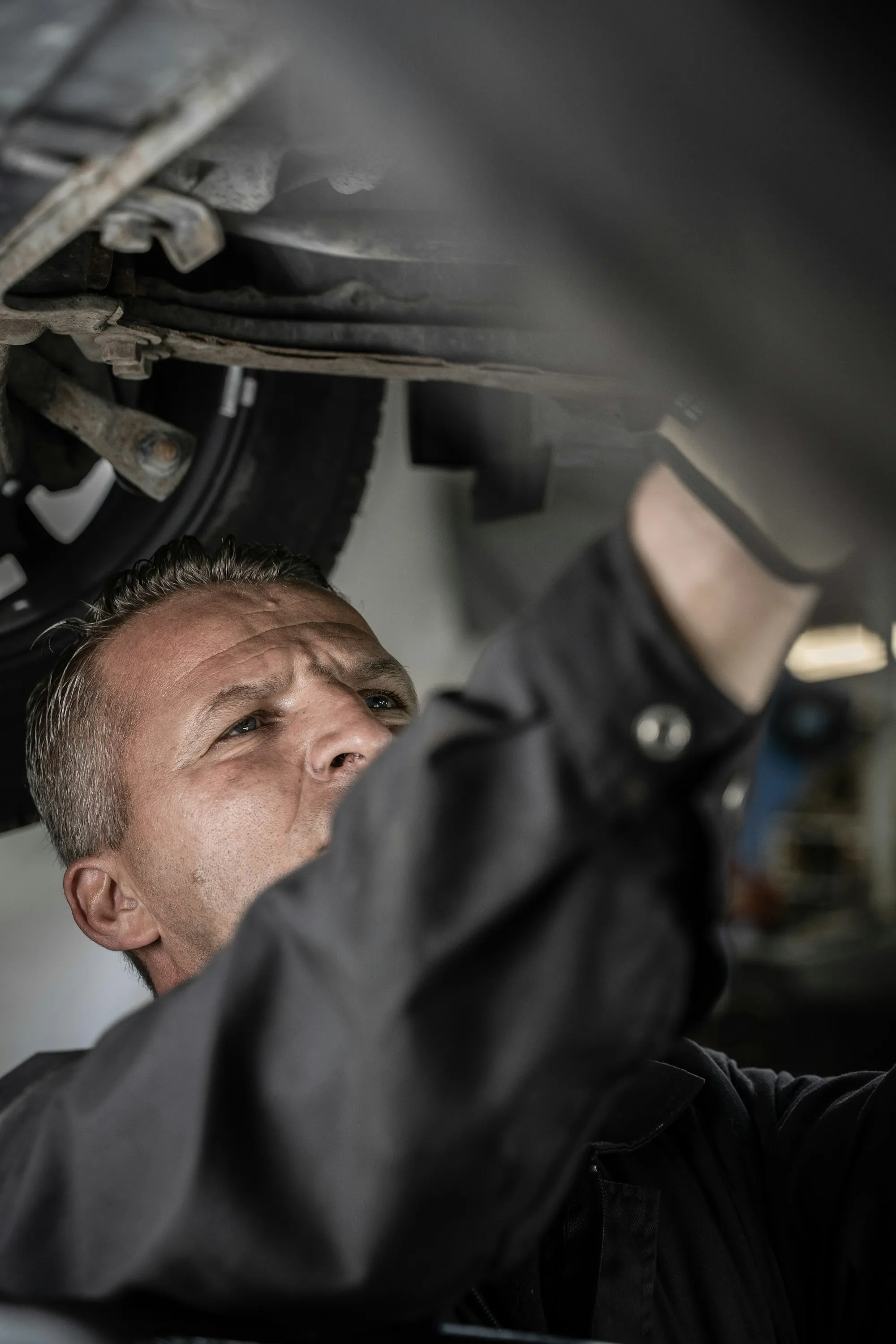 Technician working beneath a vehicle raised on a lift